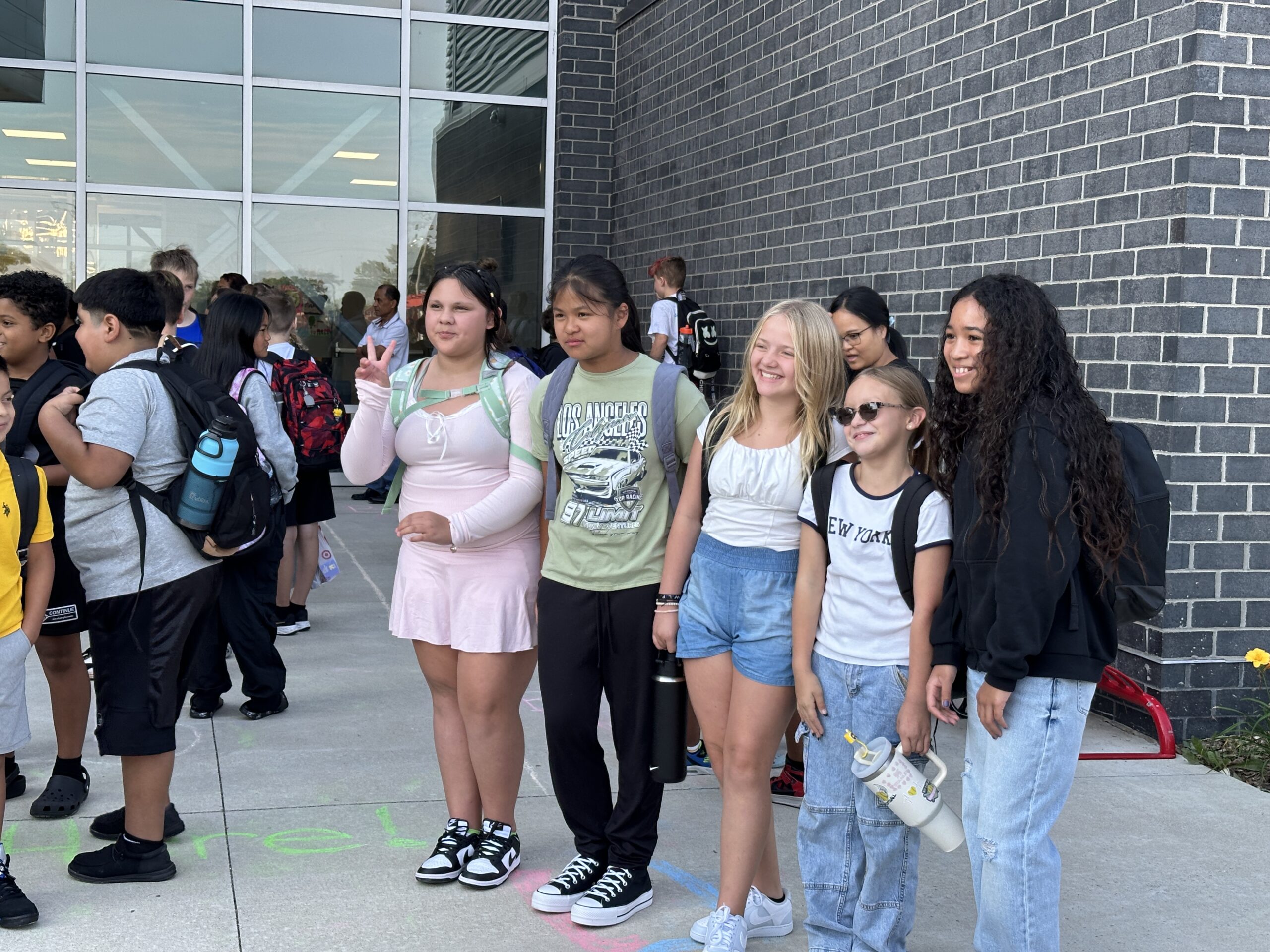 Five students pose for a picture outside of a school building