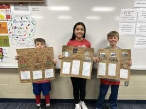 three students pose with their codices