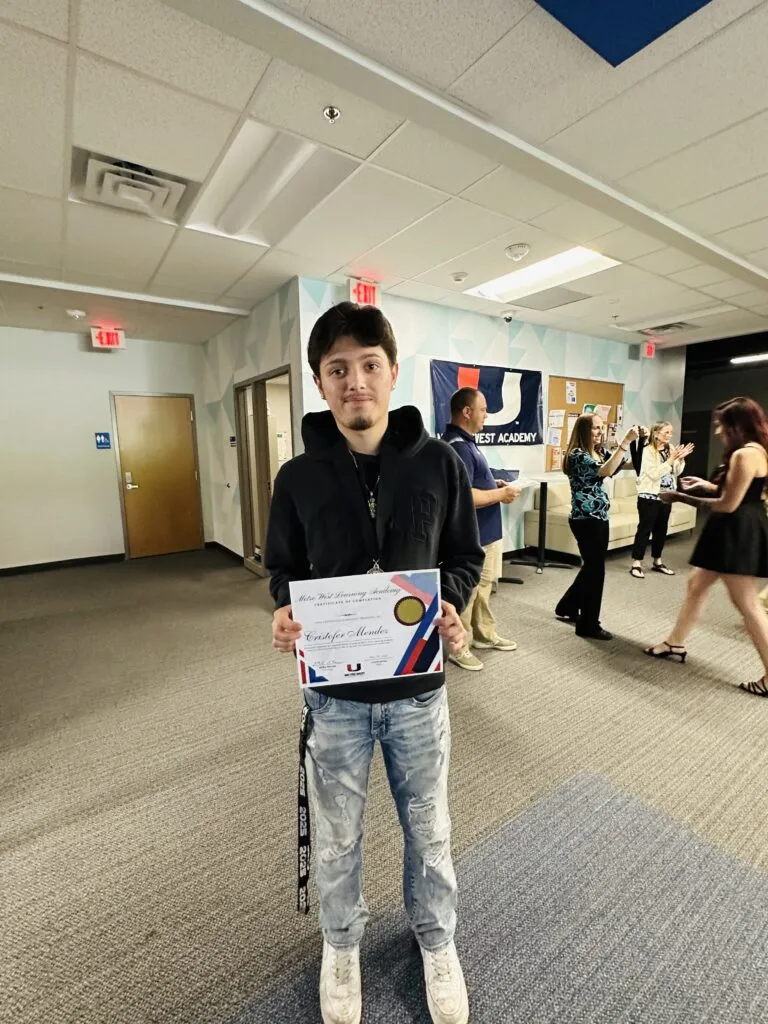 A graduating student holds up their certificate.