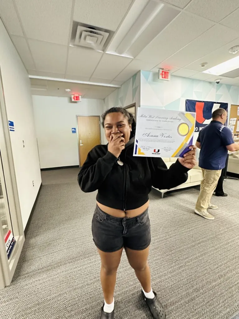 A graduating student holds up their certificate.