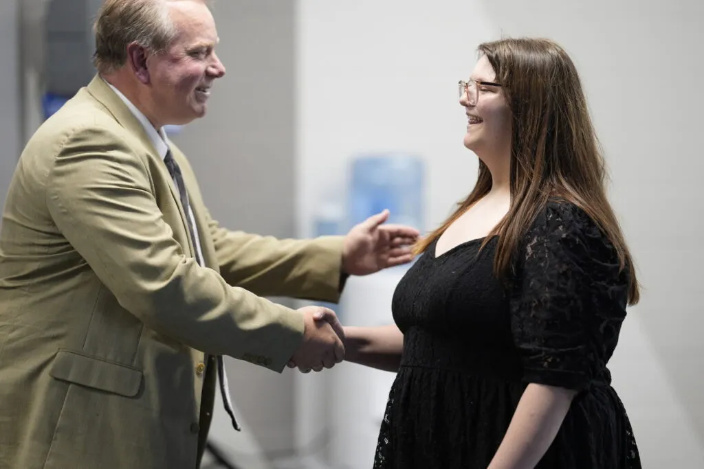 A staff member shakes a student's hand.