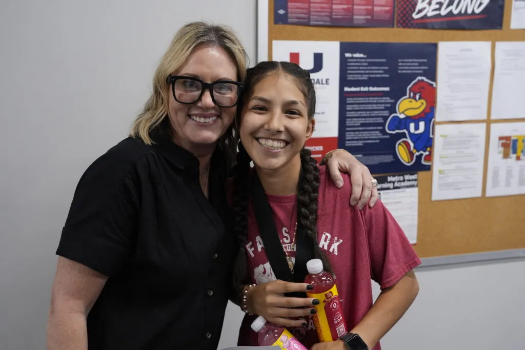 An adult smiles with a graduating student.